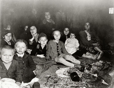 Women and children survivors sit on the floor of a barracks in the newly liberated Gunskirchen concentration camp, May 6-7, 1945.